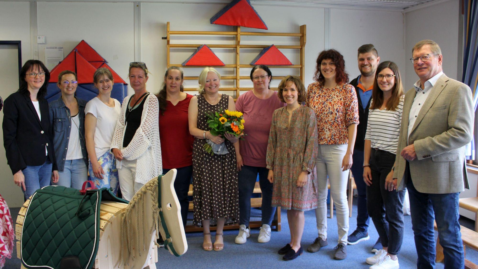 Gruppenbild mit Frau Monika Hohn, die einen Blumenstrauß hält, Bürgemeister Martin Lerbs und zehn weiteren Kolleg:innen