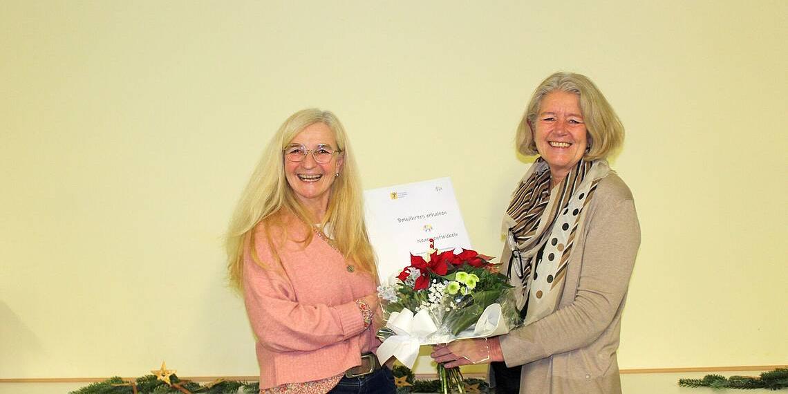 Geschäftsführerin Sabine Theisen (rechts) übergibt Karin Pauly, Pädagogische Referentin (links) einen Blumenstrauß