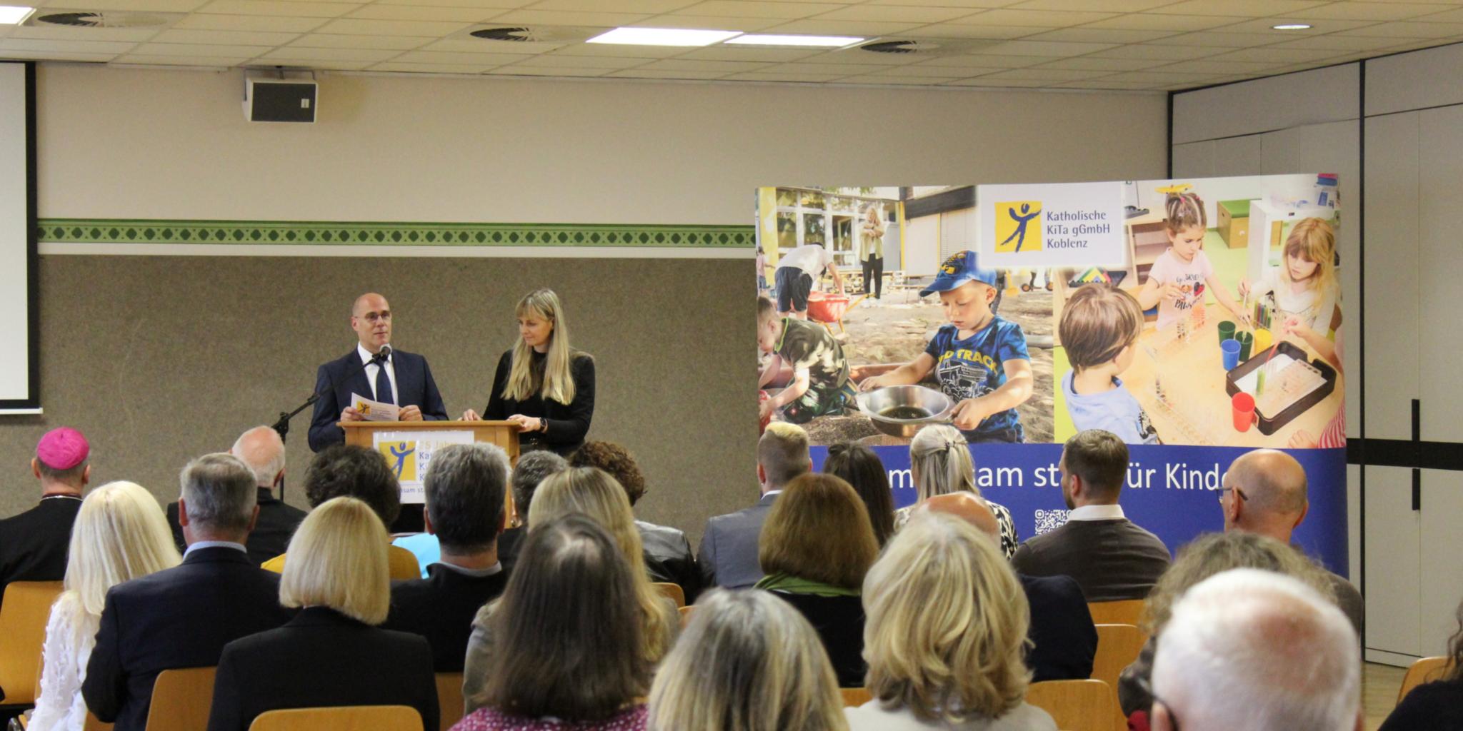 eine Frau und ein Mann, die an einem Rednerpult stehen und eine Rede halten (c) Katholische KiTa gGmbH Koblenz eine Frau und ein Mann, die an einem Rednerpult stehen und eine Rede halten