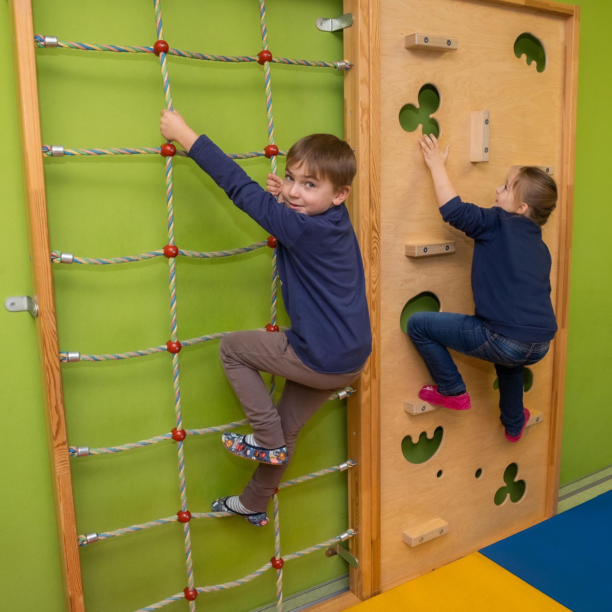 Kinder klettern eine Sprossenwand herauf