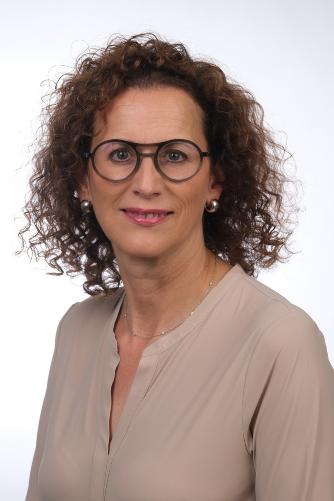 Eine Frau mit braunen Haaren, einer Brille und einem rosa Oberteil