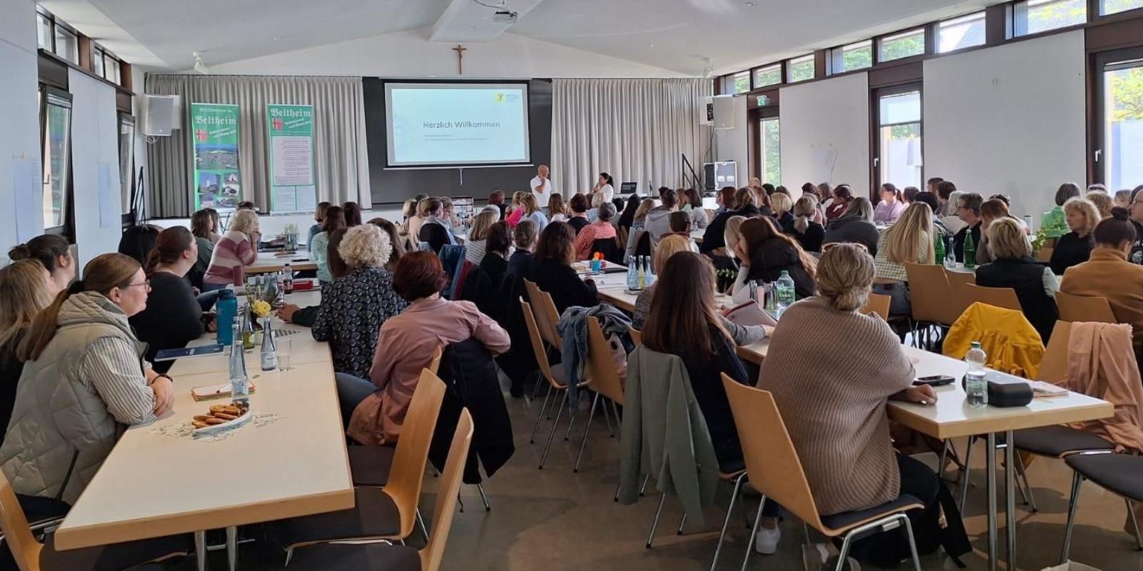 Eine Gruppe von Mitarbeitern sitzen im Schulungsraum und folgen dem Vortrag